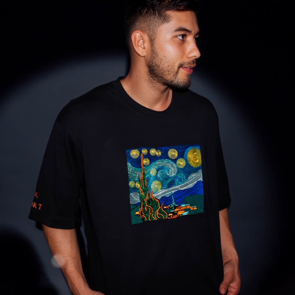 Person wearing a black t-shirt with a colorful graphic design on a dark background