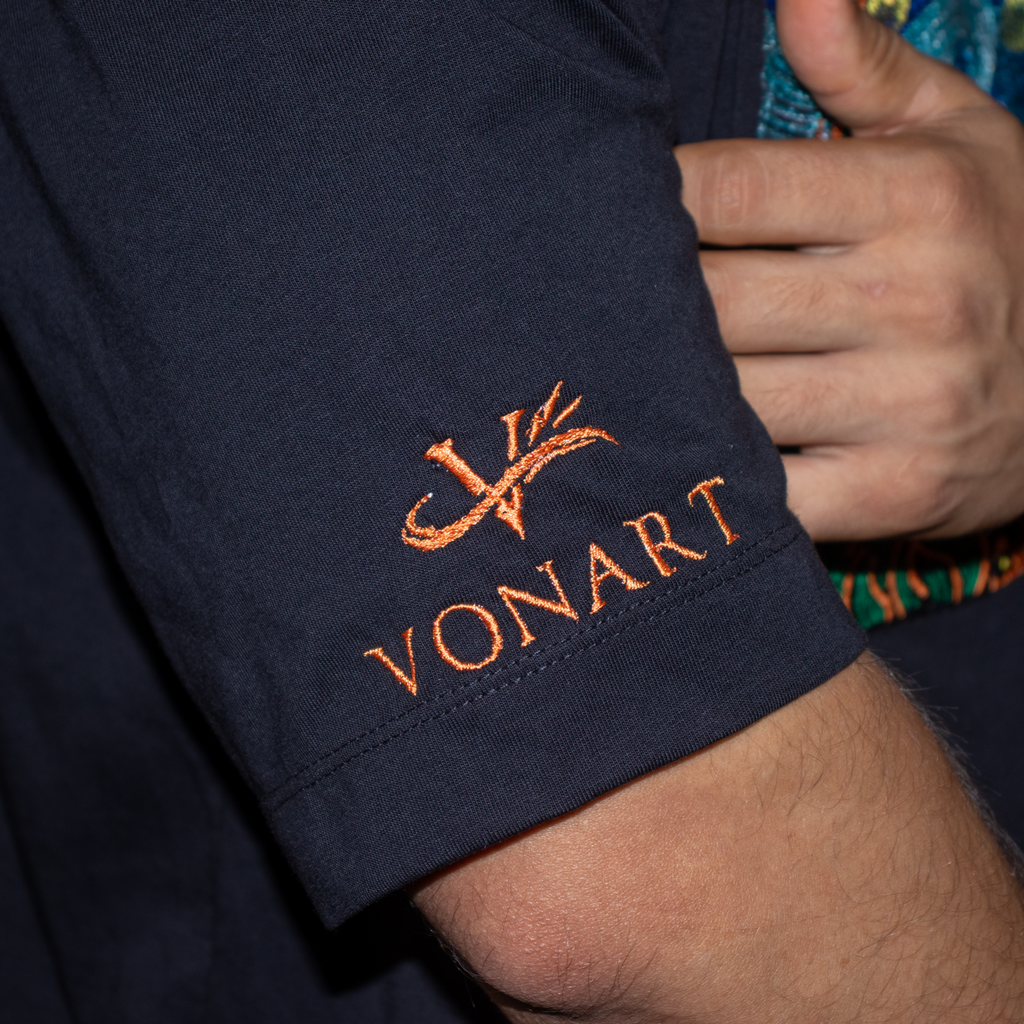 Navy blue garment with orange embroidered 'VONART' logo, held by a hand.
